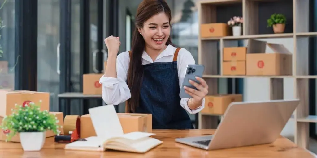 empreendedorismo-desenvolver Mulher empreendedora vibrando com nova venda online em seu negócio.